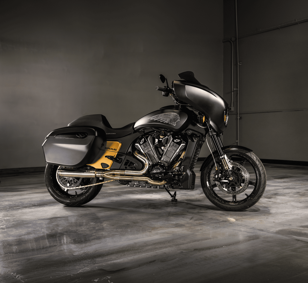 Custom matte black Indian touring motorcycle with gold accents and a Kraus-branded side panel, exposed V-twin engine, and hard saddlebag, studio shot