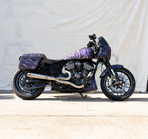 Black Sabbath x Indian Motorcycle custom Sport Chief RT with purple and blue paisley-patterned paint, photographed from the side against a white background